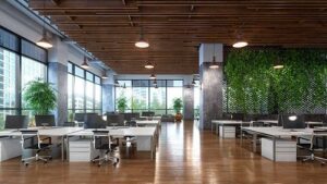 Modern open-plan office with desks, chairs, windows, and greenery