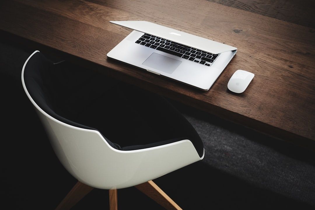 Minimalist desk with a laptop and mouse beside an empty chair